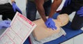 CPR First Aid training concept. Back view of woman holding first aid instruction during cpr training class. Royalty Free Stock Photo