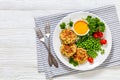 crab cakes with sauce, green peas, tomatoes