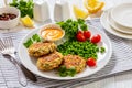 crab cakes with sauce, green peas, tomatoes