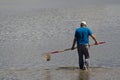 A crab hunter in shallow water with a net