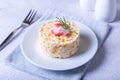 Crab salad with corn and eggs on a white plate. Serving in portions. Traditional Russian salad.