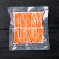 Crab stick surimi vacuum pack, on black wooden table background, top view flat lay