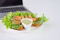 Crab stick and vegetables salad in noodle tube on white dish near laptop Royalty Free Stock Photo