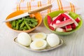 Crab sticks, green beans in bowls, boiled eggs in plate, knife, napkin on table Royalty Free Stock Photo