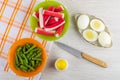 Crab sticks, green beans in bowls on napkin, salt, boiled eggs in plate, knife on table. Top view Royalty Free Stock Photo