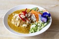 Crabmeat curry sauce with fermented rice noodle and side dishes in white plate on the wooden table.