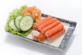 Crabmeat sticks with sliced cucumber and tomato on plate