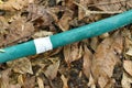 Crack green watering rubber tube repairing by white tape roll with dry leaf on frontyard garden ground