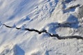 Crack in ice on a frozen lake or river in winter. Snow background, texture Royalty Free Stock Photo