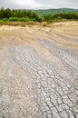 Cracked, arid terrain with dry grass in the backdrop