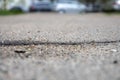 Cracked asphalt in the city, cracks and potholes on the road, taken from the bottom point, visible horizon line, selective focus.