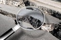 Cracked asphalt road damaged after a structural failure - Concept image seen through a magnifying glass