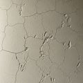 Cracked, beige painted wall with a textured, rough surface. The network of irregular, jagged lines Royalty Free Stock Photo