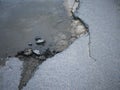 Cracked and broken asphalt pothole with water on the surface of Royalty Free Stock Photo