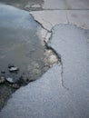 Cracked and broken asphalt pothole with water on the surface of Royalty Free Stock Photo