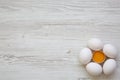 Cracked chicken egg among other eggs on white wooden background, top view. Royalty Free Stock Photo