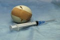 a cracked chicken egg sealed with a medical plaster next to a syringe concept vaccination immunization medical care