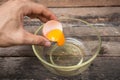 Cracked chicken egg with yolk and egg shell on dish, wooden background Royalty Free Stock Photo