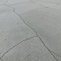 Cracked concrete surface displaying a network of irregular, thin fissures. The texture is Royalty Free Stock Photo