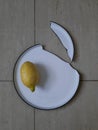 Cracked dining plate lays on a tile. Yellow lemon on a broken ceramic plate. Dish broke into two pieces. Accident in the kitchen Royalty Free Stock Photo