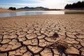 Cracked earth with dried up lake in background. Global warming and water scarcity concept Royalty Free Stock Photo