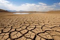 Cracked earth with dried up lake in background. Global warming and water scarcity concept Royalty Free Stock Photo