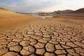 Cracked earth with dried up lake in background. Global warming and water scarcity concept Royalty Free Stock Photo