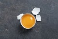 Cracked eggshell with raw yolk on grey table, top view
