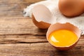 Cracked eggshell with raw yolk on wooden table, closeup. Space for text Royalty Free Stock Photo