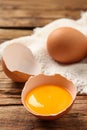 Cracked eggshell with raw yolk on wooden table, closeup. Space for text Royalty Free Stock Photo