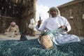 cracked foot of an omani man reparing a fish net