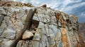 A cracked and fractured rock face with deep crevices and loose boulders precariously perched on top. The instability is