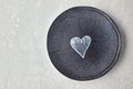 Cracked gray ceramic plate with painted white heart on stone table. Top view with copy space Royalty Free Stock Photo