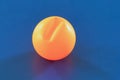 A cracked orange ping pong ball