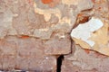 Cracked paint, plaster of soft yellow-red pastel color on brick wall surface close up detail, grunge horizontal background Royalty Free Stock Photo