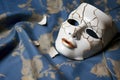 a cracked porcelain mask laying on a velvet cloth