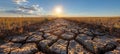 Cracked road cutting through field under sunny sky with clouds Royalty Free Stock Photo