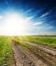 Cracked road in green grass at sunset in a blue sky Royalty Free Stock Photo