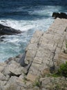 Cracked rock on ocean`s edge with eddying water