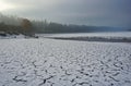 Cracked and snowy empty bottom of a dam - a silent cloudy winter country