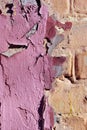 Cracked soft pink paint, plaster surface on yellow brick wall, grunge vertical shabby background detail Royalty Free Stock Photo