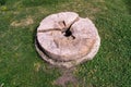 Cracked stone millstone lies on the grass of the yard Royalty Free Stock Photo