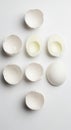 Cracked and uncracked white egg shells are arranged on a white surface, forming a visually balanced Royalty Free Stock Photo