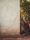 A cracked wall with wheelbarrows and tools leaning against it in