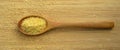 Cracked wheat daliya grains in wooden spoon, on bamboo cutting board Royalty Free Stock Photo