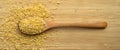 Cracked wheat daliya grains in wooden spoon, on bamboo cutting board Royalty Free Stock Photo