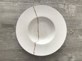 A cracked white bowl repaired using gold powder following the Japanese art of kintsugi Royalty Free Stock Photo