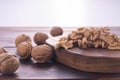 Cracked and whole walnuts on cutting board and wooden table, side view on white background. Healthy nuts and seeds Royalty Free Stock Photo