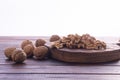 Cracked and whole walnuts on cutting board and wooden table, side view on white background. Healthy nuts and seeds Royalty Free Stock Photo