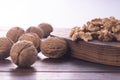 Cracked and whole walnuts on cutting board and wooden table, side view on white background. Healthy nuts and seeds Royalty Free Stock Photo